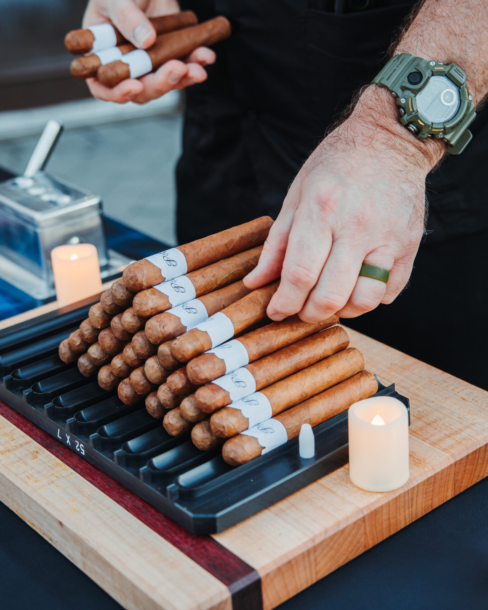 a cigar roller displaying a stack of rolled cigars on a table for a wedding